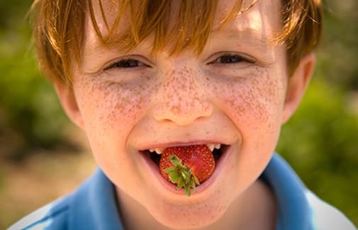 Kid smiling eating a strawberry in Byron Georgia